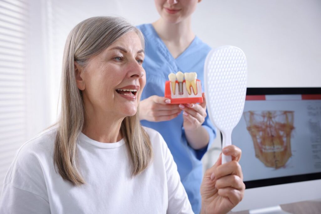 Patient discussing dental implants with a dental professional while viewing an implant model