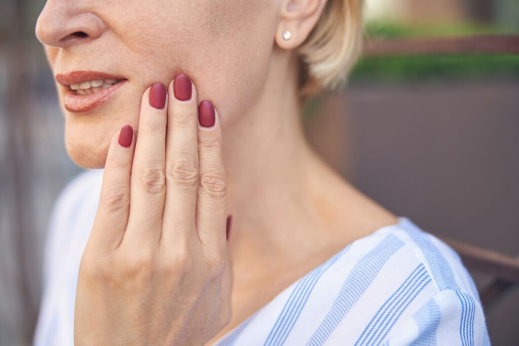 Woman experiencing tooth pain and touching her cheek