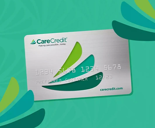CareCredit card displayed on teal background with green leaf design elements.