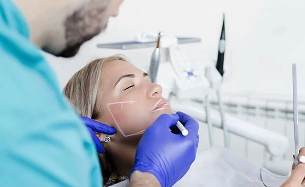 Dental professional in blue gloves examining patient's mouth in clinical setting.