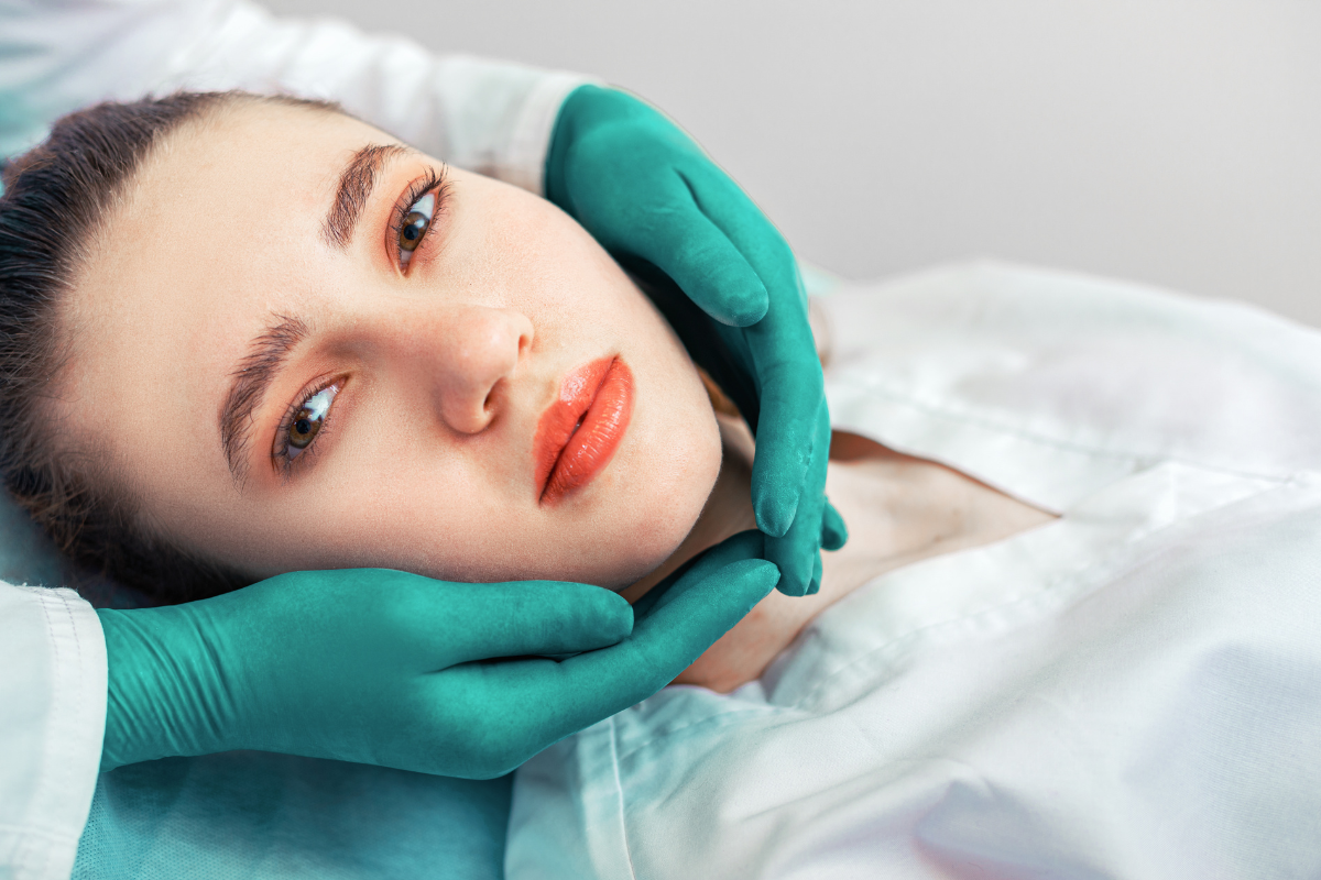 Cosmetic dentist examining patient's jaw alignment and facial structure during consultation.